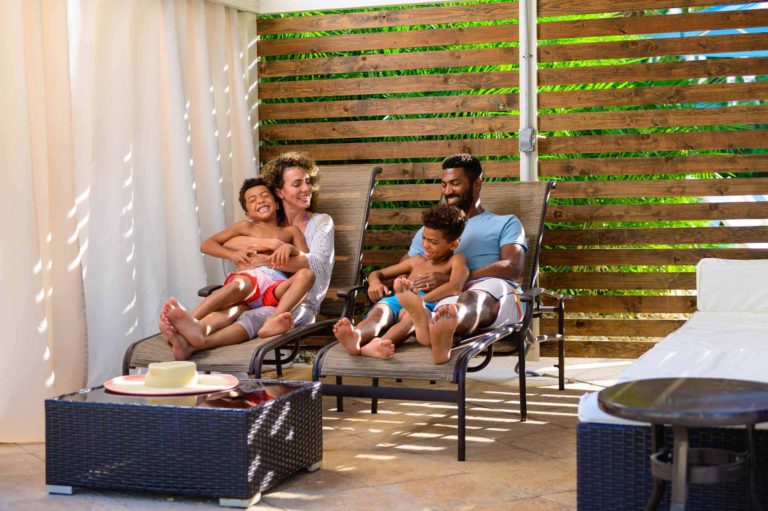 Family relaxing in lounge chairs inside their private cabana at the Encore Resort Water Park