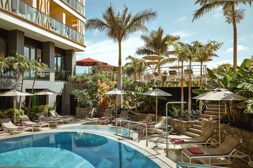 Piscina del hotel Bohemia Suites & Spa rodeada de palmeras y tumbonas