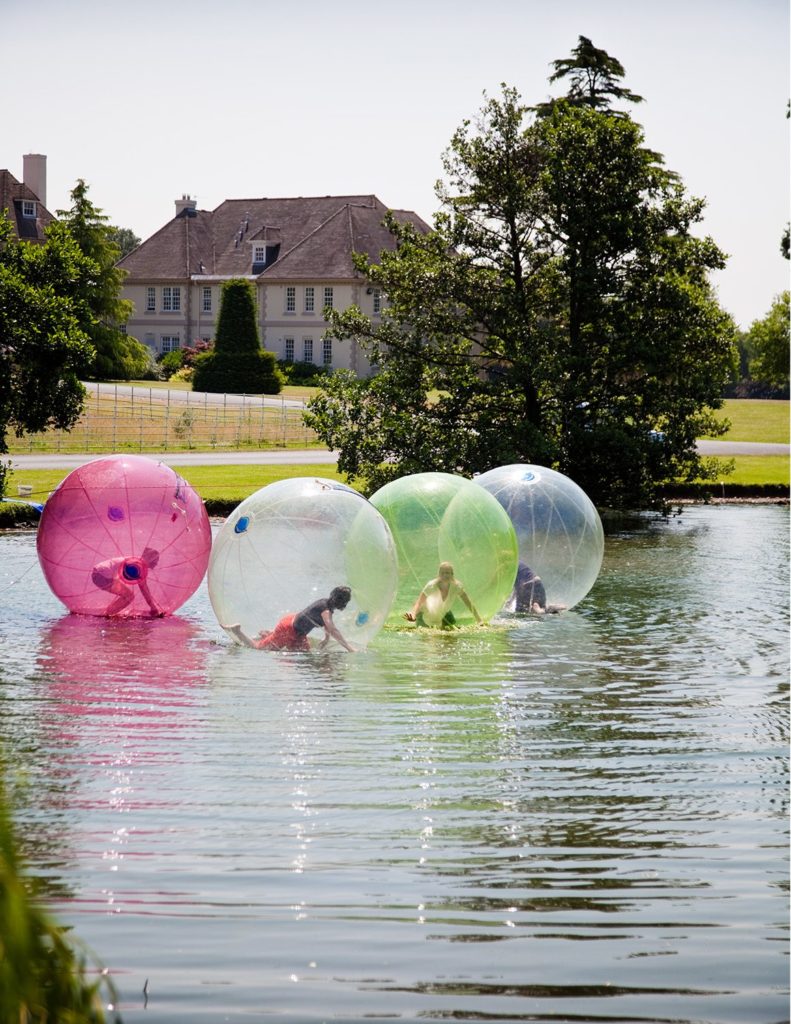Gruppe von Menschen in aufblasbaren Plastikblasen auf dem See außerhalb der Brockencote Hall