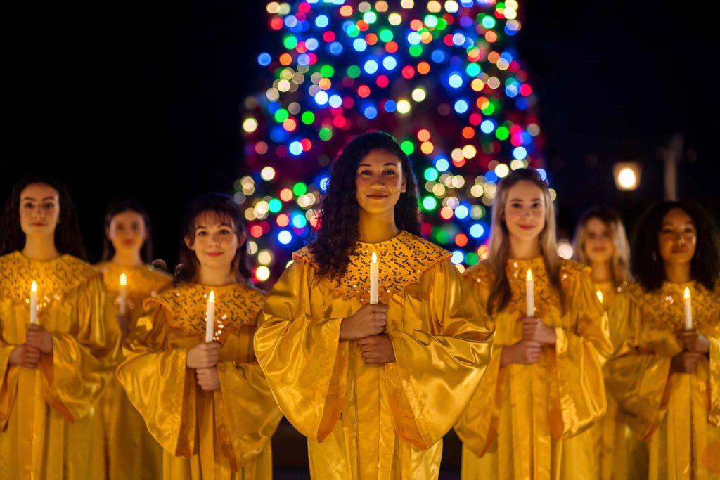 Grupo de personas que visten túnicas navideñas amarillas para el EPCOT Candlelight Processional