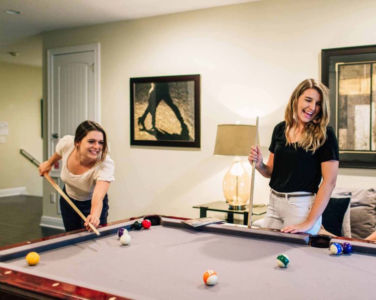 Young woman playing pool in their private resort home at Encore Resort at Reunion