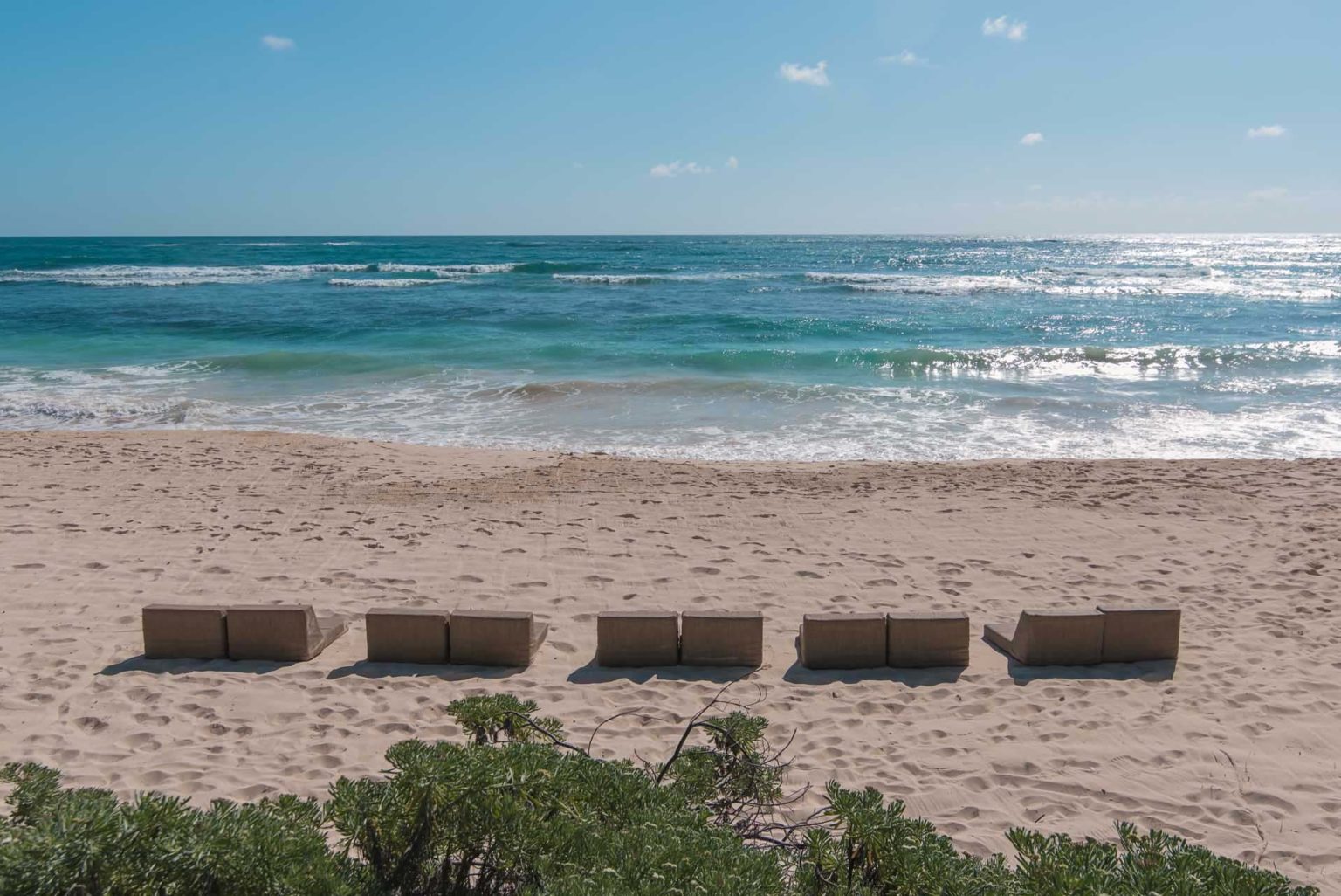 Pairs of lounge chairs on the beach at the Papaya Playa Project