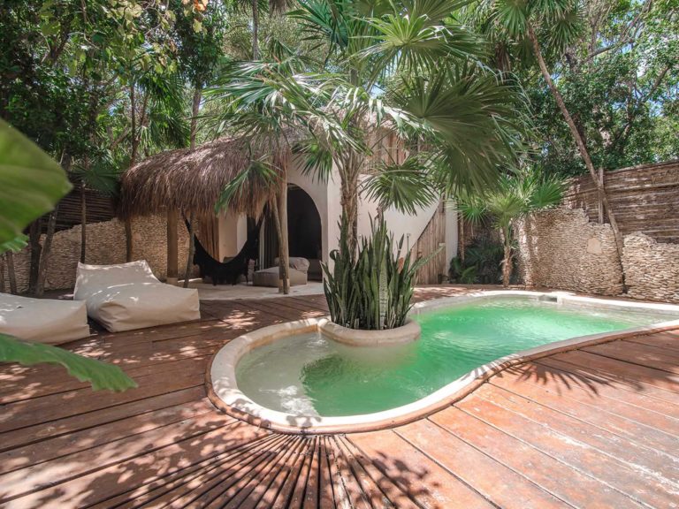 Casita jungle view with pool with covered outdoor sitting area, hammock, and lounge chairs at the Papaya Playa Project
