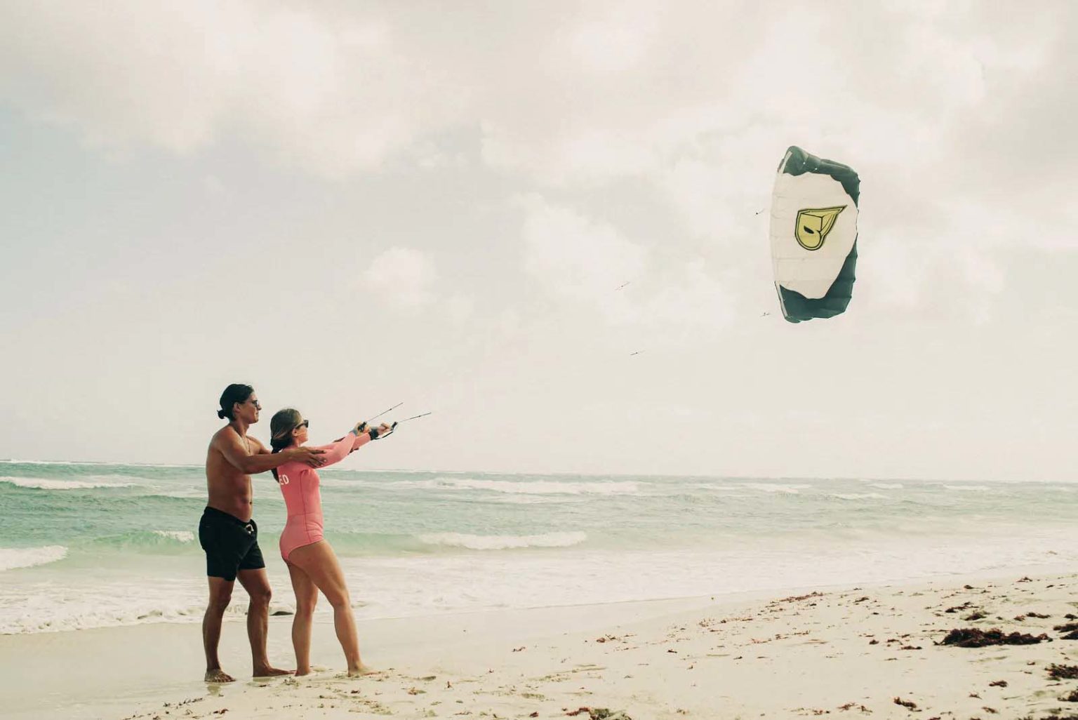 Couple flying a kite on the beach at the Papaya Playa Project
