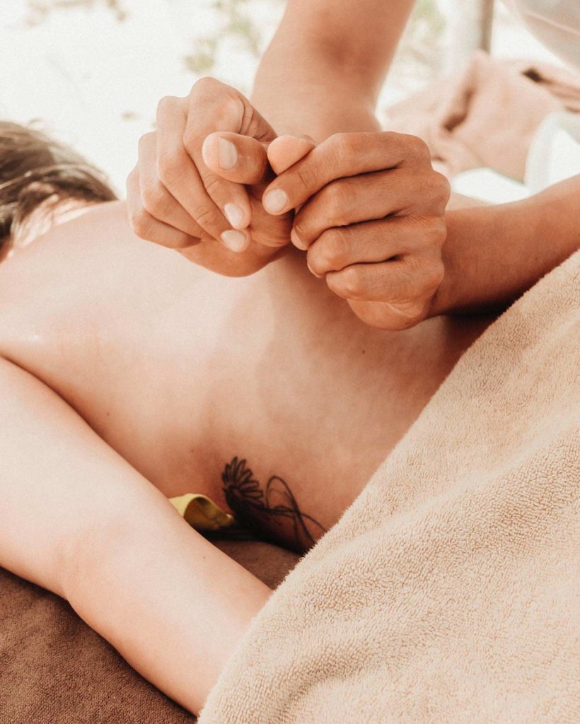 Woman receiving a back massage treatment at the Papaya Playa Spa