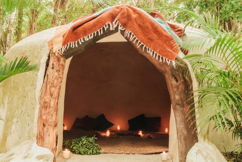 Temazcal forrado con tapetes, velas y almohadas en el Proyecto Papaya Playa