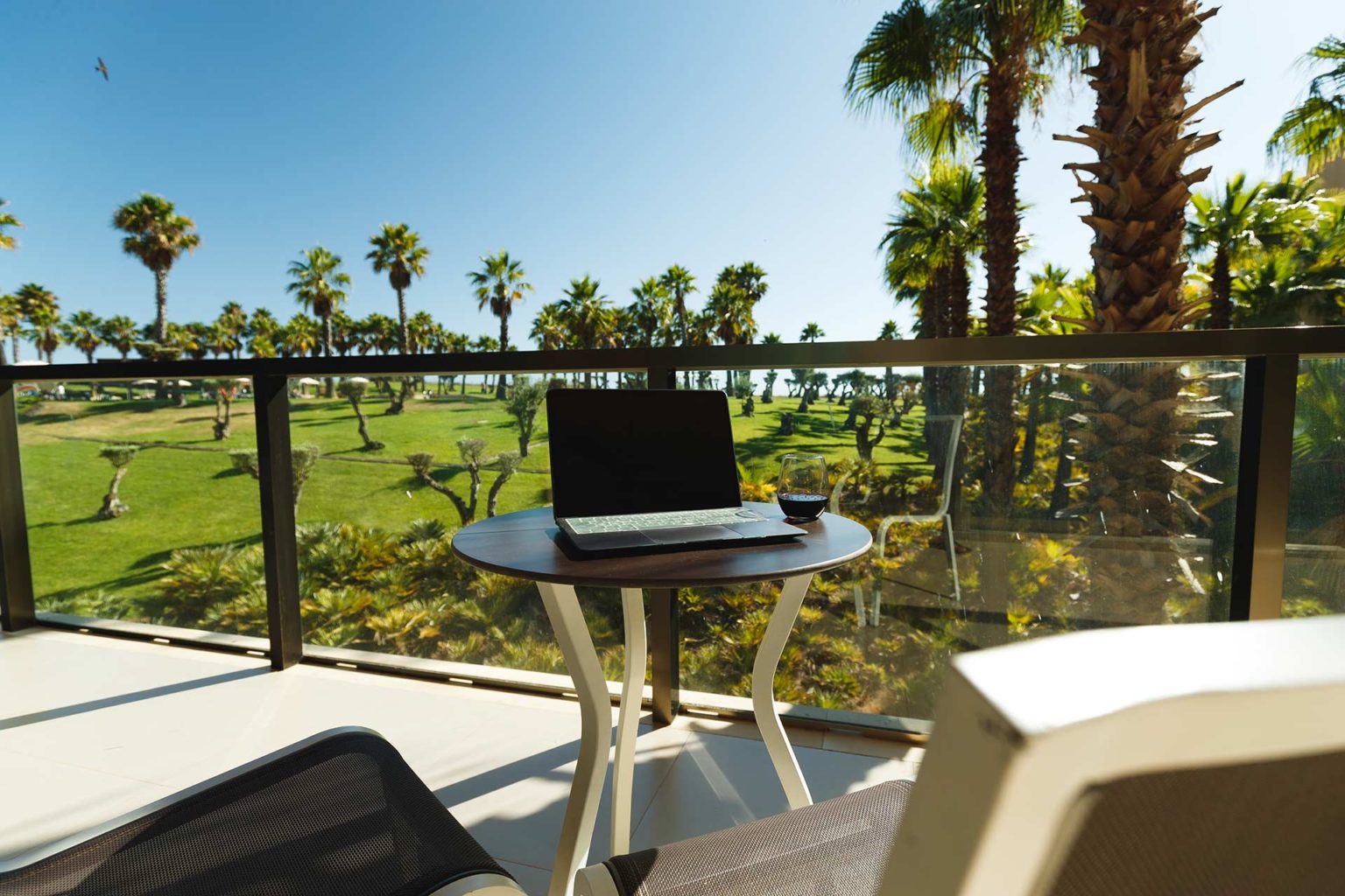 Laptop and a glass of wine set on a private patio of a Salgados Dunas suite