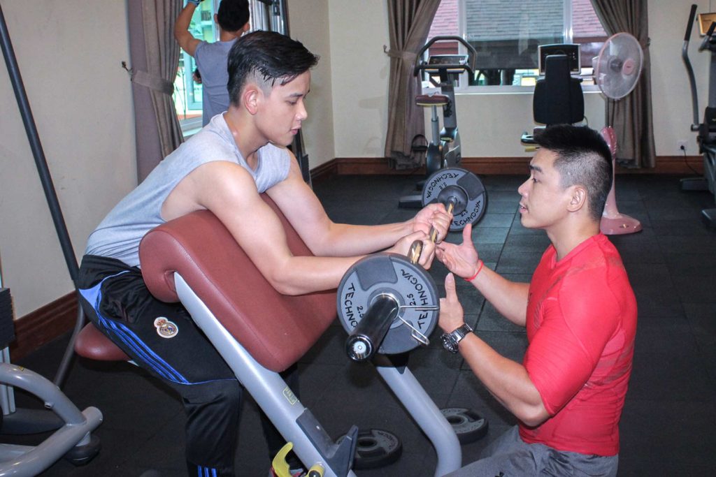 Trainer, der beim Gewichtheben im Fitnesscenter des Sokha Siem Reap Resort hilft
