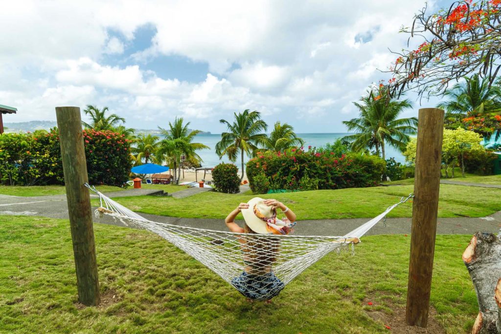 Woman wearing a sun hat relaxing on a hammock with ocean views at Calabash Cove