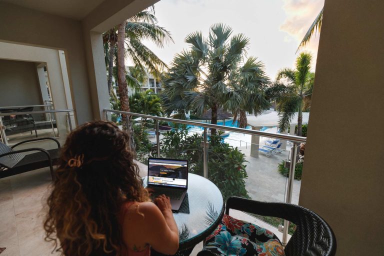 Femme travaillant sur un ordinateur portable assise sur sa terrasse privée à l'Atrium Resort