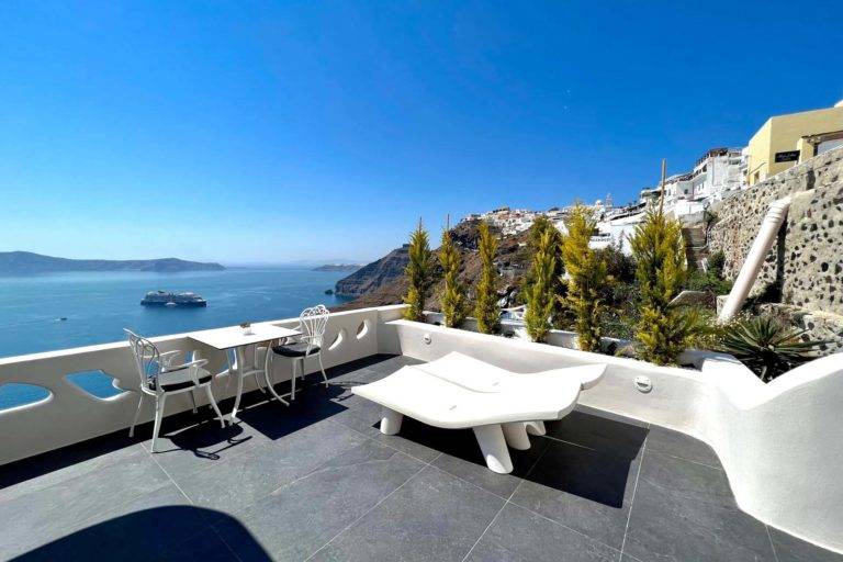 Cave Honeymoon Suite - Balcón al aire libre con mesa de comedor y sillones con vista al mar | Suites de lujo Athina