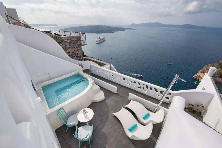 Suite Cave - Balcón al aire libre con mesa de comedor, sillones, jacuzzi y vista al mar | Suites de lujo Athina