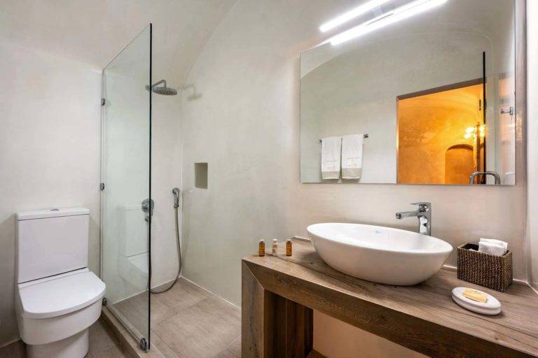 Suite Deluxe - Baño con ducha de lluvia, inodoro, tocador, espejo y artículos de tocador | Suites de lujo Athina