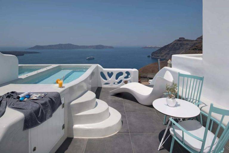 Grand Cave Suite - Balcón al aire libre con mesa de comedor, sillones y jacuzzi con vista al mar | Suites de lujo Athina