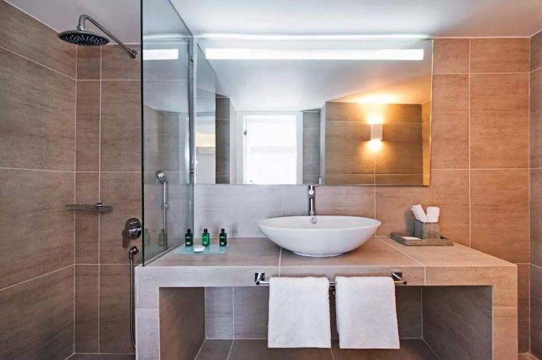 Master Loft Suite - Baño con ducha de lluvia, ducha de mano, tocador, espejo y artículos de tocador | Suites de lujo Athina