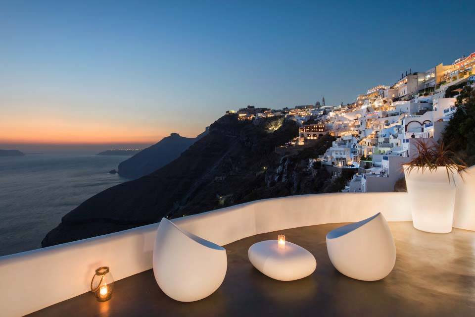 Zona de estar al aire libre con vistas a los acantilados junto al mar ya la ciudad de Fira, Santorini, Grecia | Suites de lujo Athina