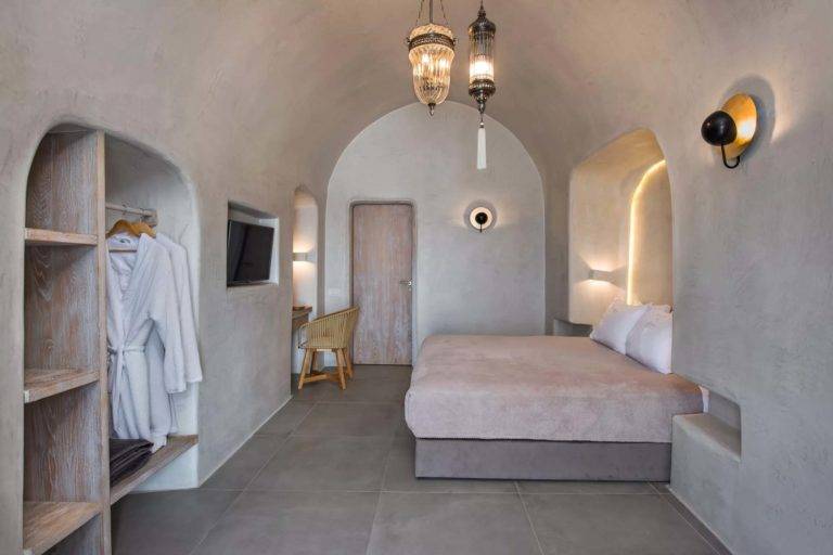 Petit Cave Suite - Dormitorio con cama doble, TV, estación de trabajo y armario abierto | Suites de lujo Athina
