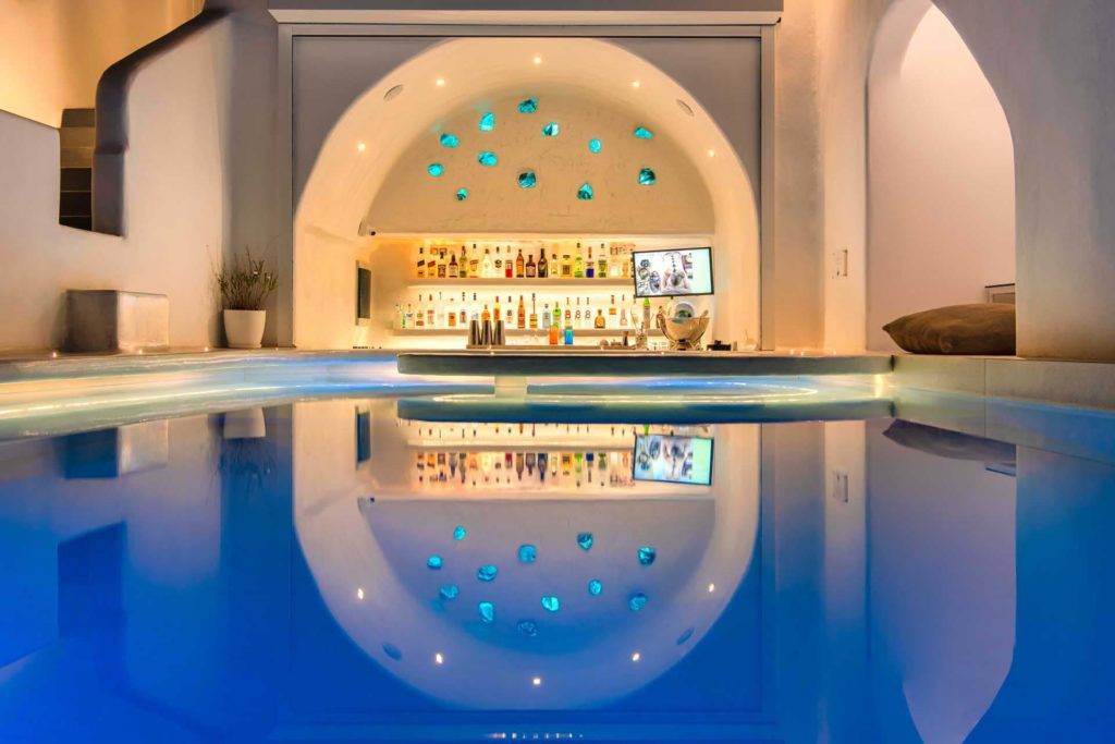 El bar de la piscina iluminado por la noche en Athina Luxury Suites