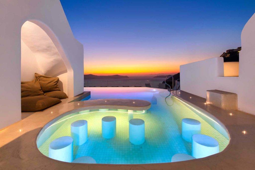 Asientos en la piscina con vistas al atardecer sobre el océano en Athina Luxury Suites