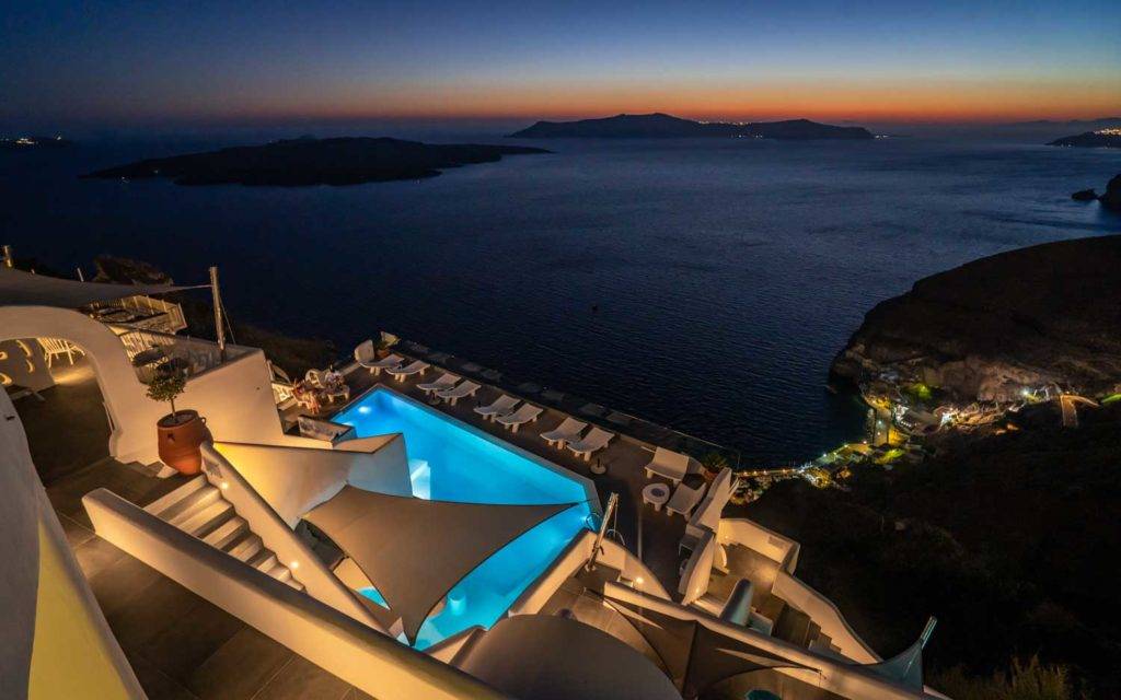 Vista nocturna de la piscina y la terraza de la piscina de Athina Luxury Suites.
