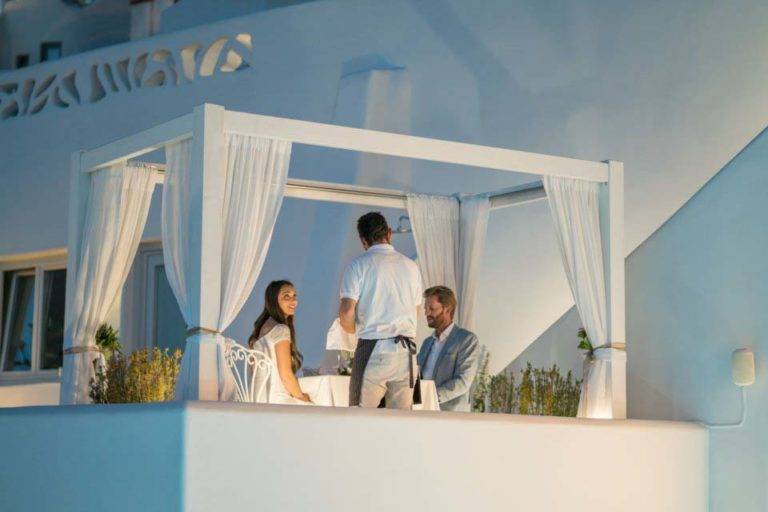 Una pareja disfruta de una cena privada a la luz de las velas en un balcón de Athina Luxury Suites