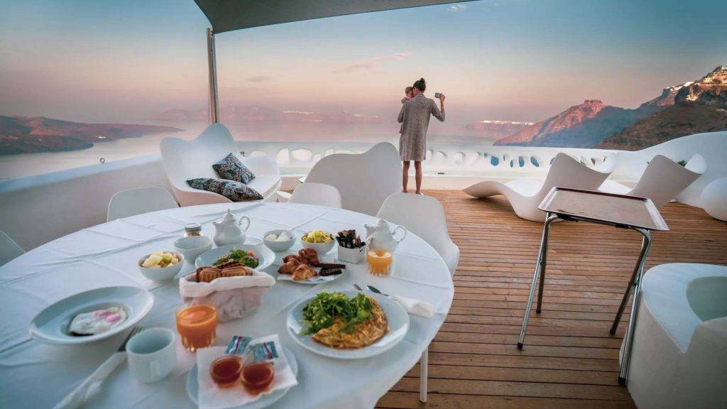 Royal Suite - Madre con bebé en el balcón con desayuno en la mesa en la suite | Suites de lujo Athina