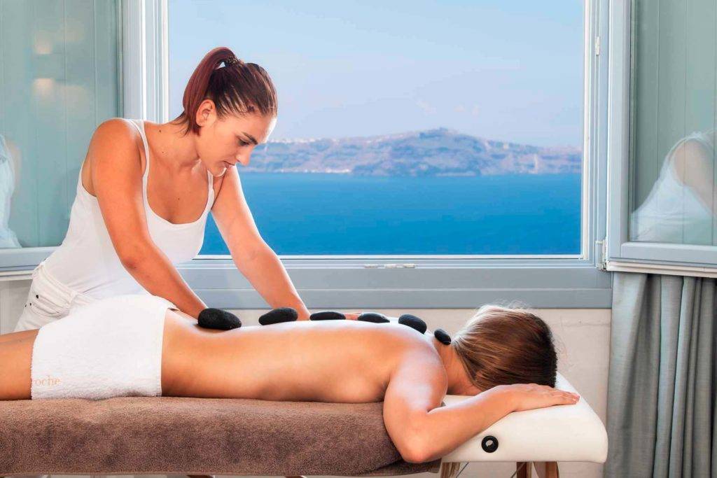 Mujer recibiendo un masaje con piedras calientes en el spa Athina Luxury Suites