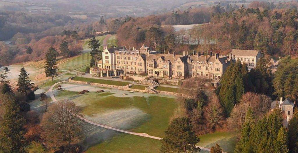 Aerial view of Bovey Castle exterior with expansive green and castle wall