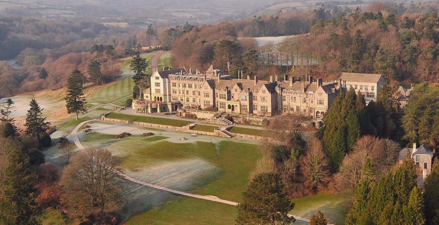 Aerial view of Bovey Castle exterior with expansive green and castle wall