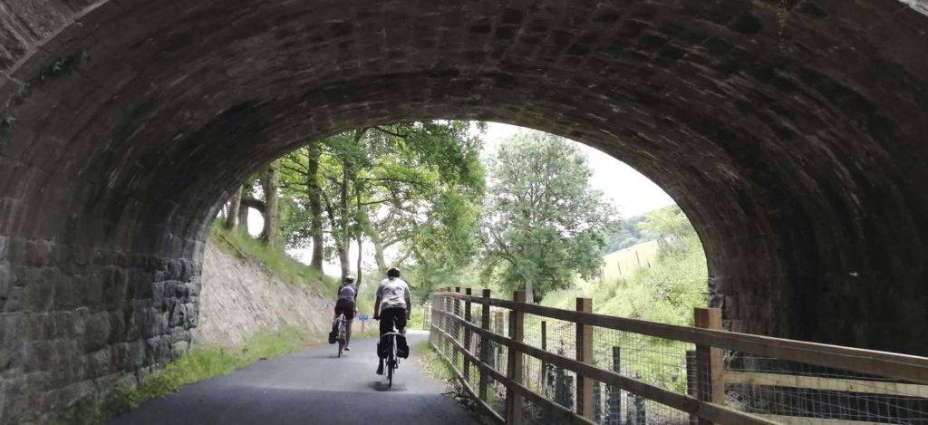 Couple bike riding on a trail going under a bridge | Bovey Castle