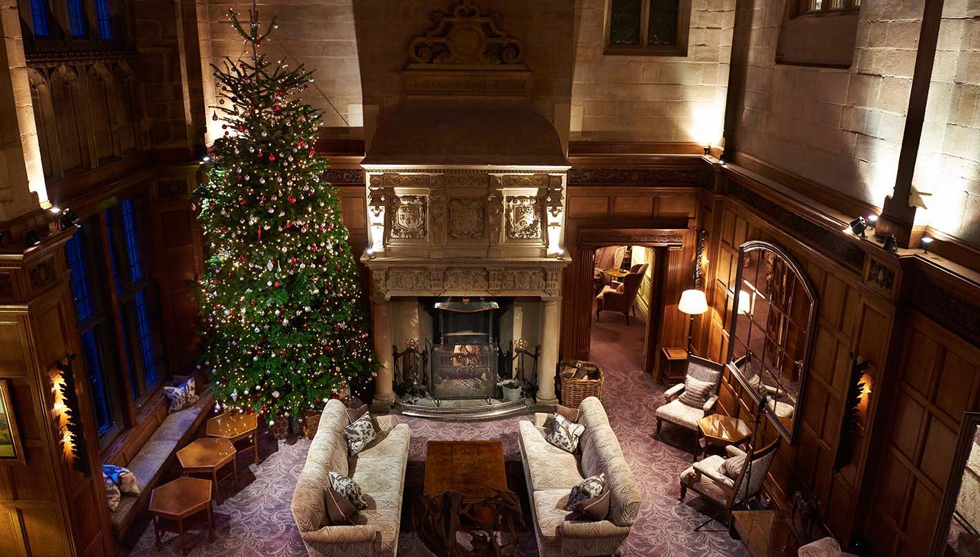 Bovey Castle interior grand living room with high ceiling, fireplace, and large Christmas Tree