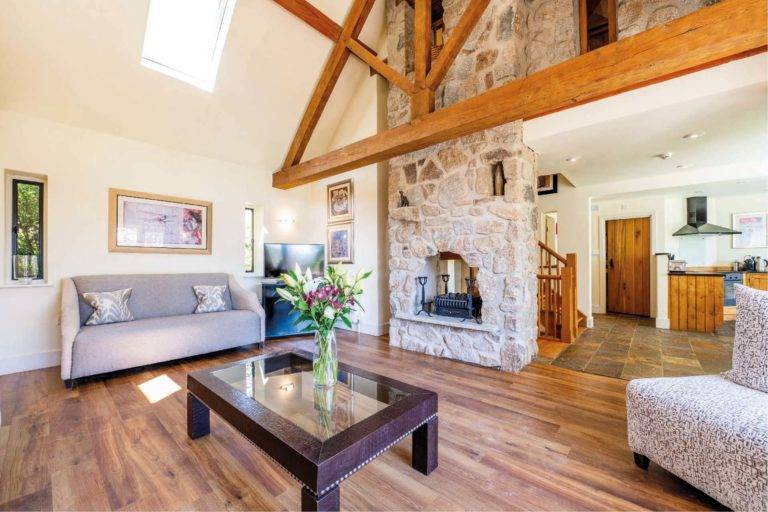 Castle Lodge - Open concept living room with a fireplace and exposed wood beams | Bovey Castle