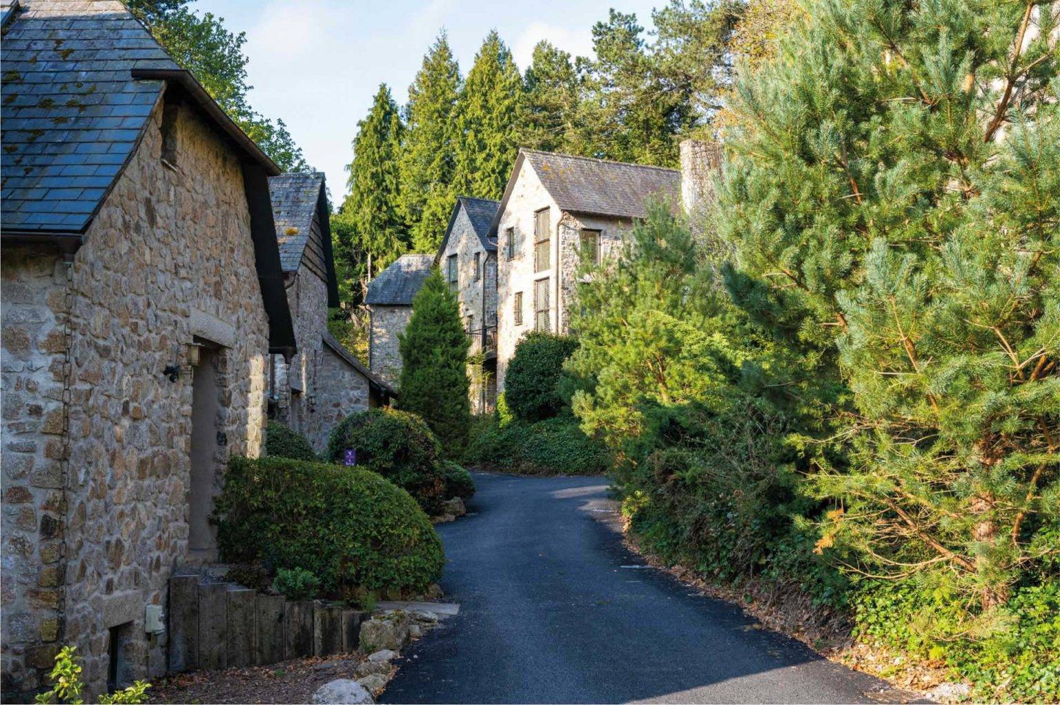 Street of stone brick Castle Lodges surrounded by evergreen trees at Bovey Castle