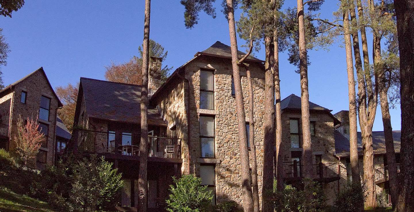 Stone brick Castle Lodges surrounded by evergreen trees at Bovey Castle