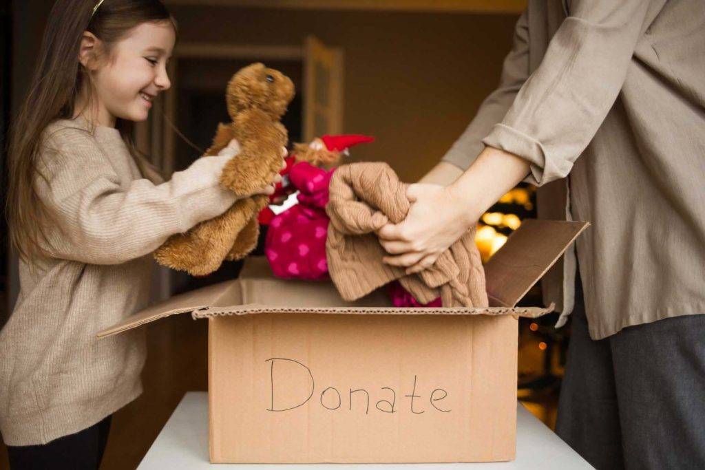 Jeune fille mettant des jouets dans une boîte de donation