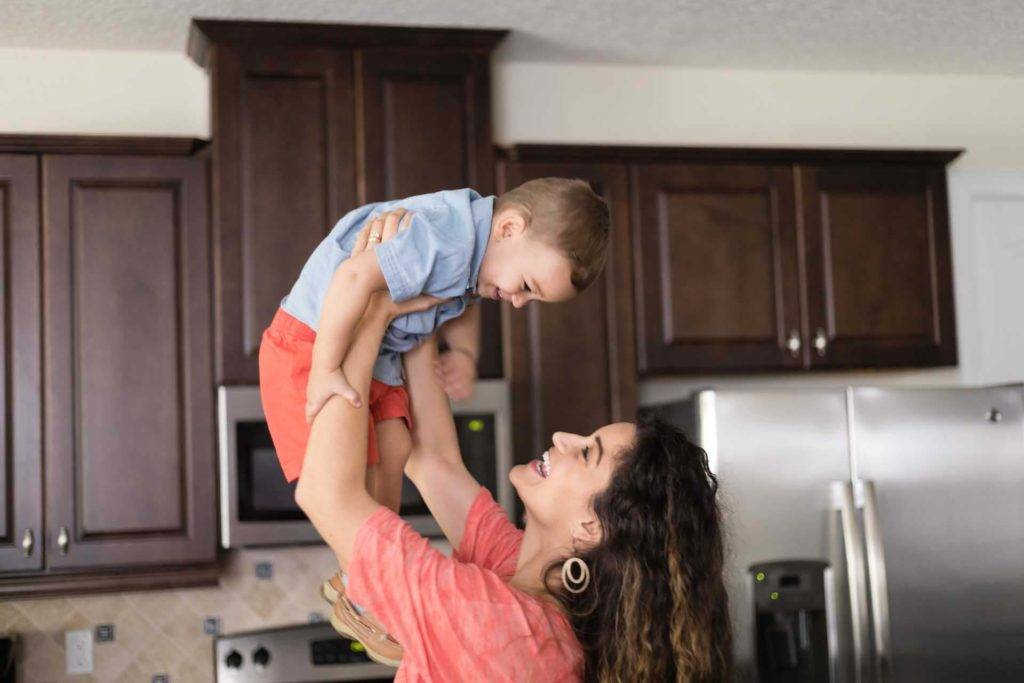Mother lifting up her smiling son in their Encore Resort kitchen