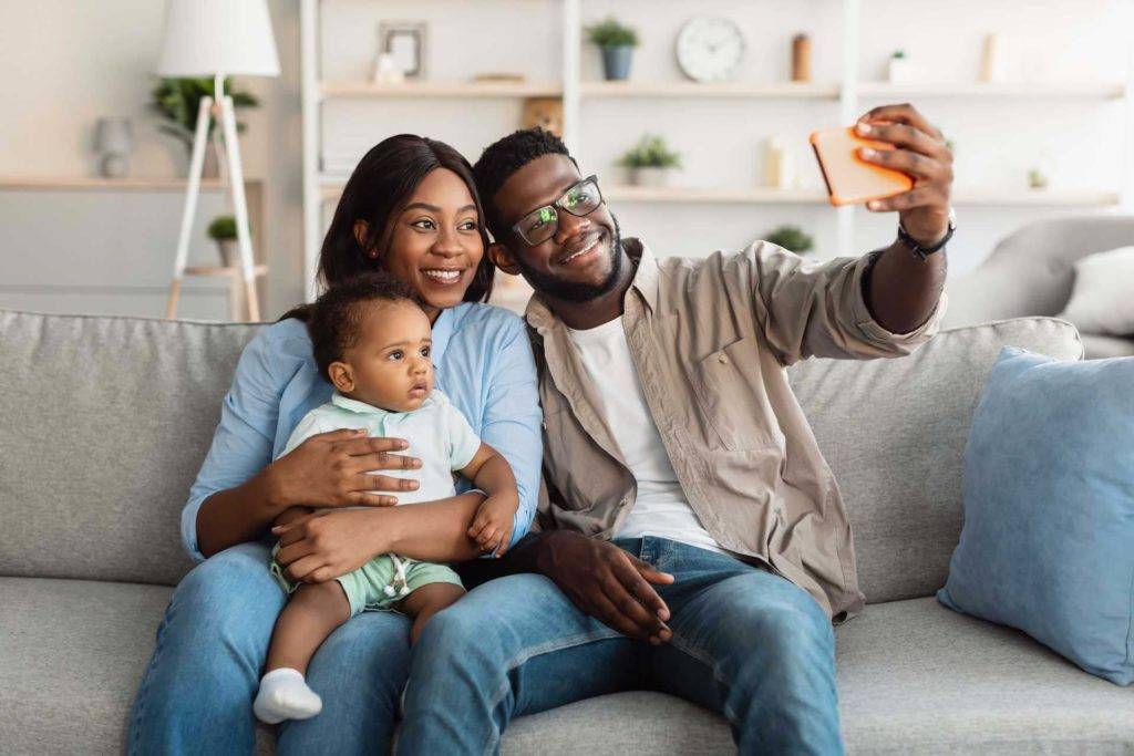 Familia de tres tomándose una selfie en el sofá de su sala
