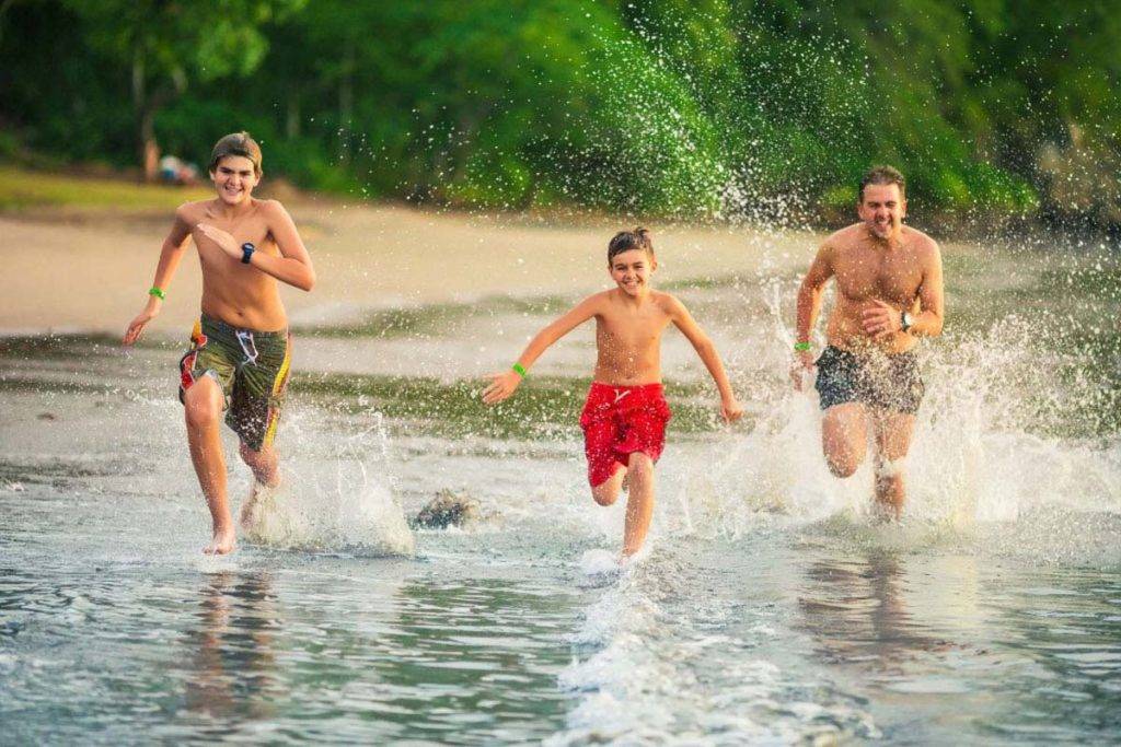 Hermanos corriendo por la playa en traje de baño | Los Sueños Resort & Marina