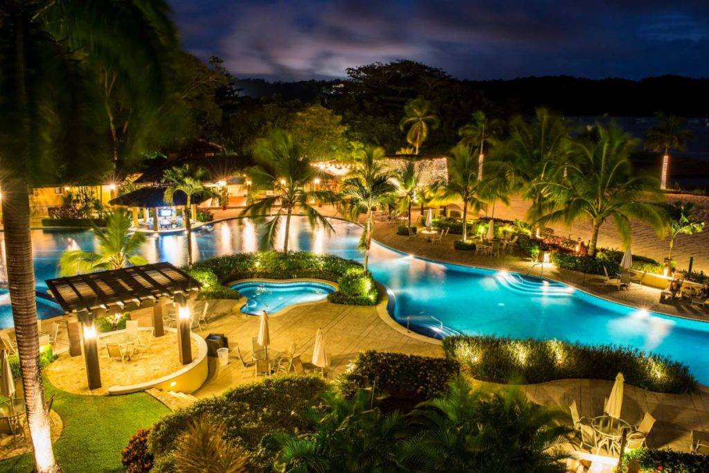 Vista aérea nocturna de la piscina al aire libre en Los Sueños Beach Club