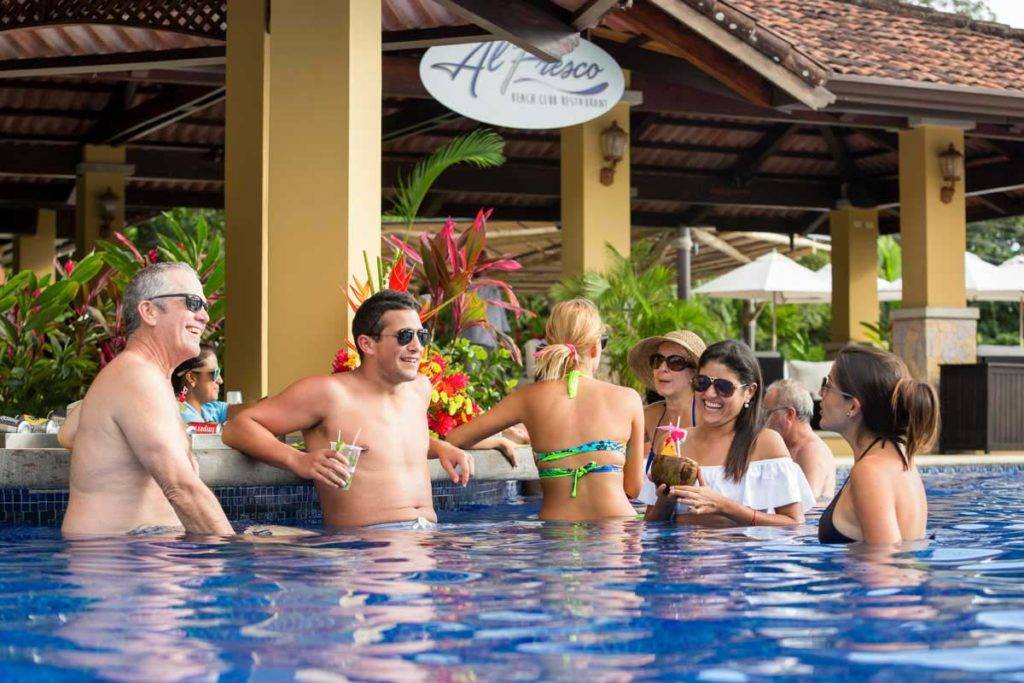 Grupo de personas tomando cócteles en el bar de la piscina de Los Sueños Beach Club