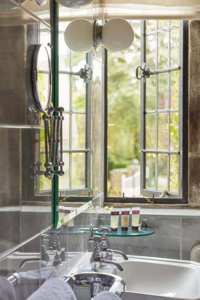 Habitación Clásica - Baño con lavabo, artículos de tocador, espejo de maquillaje y ventana abierta | Tribunal Mallory