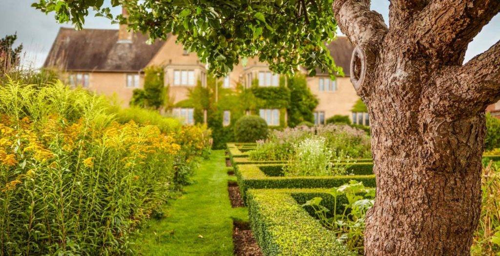 Jardines ingleses tradicionales de Mallory Court con setos recortados, árboles y flores