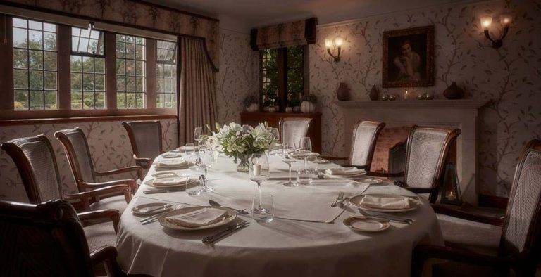 Large, set dining table in a private dining room with fireplace at Mallory Court