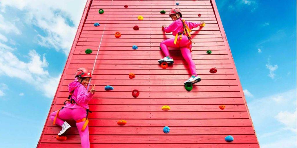 Mother and daughter in climbing gear, going up on a climbing wall | Nemacolin