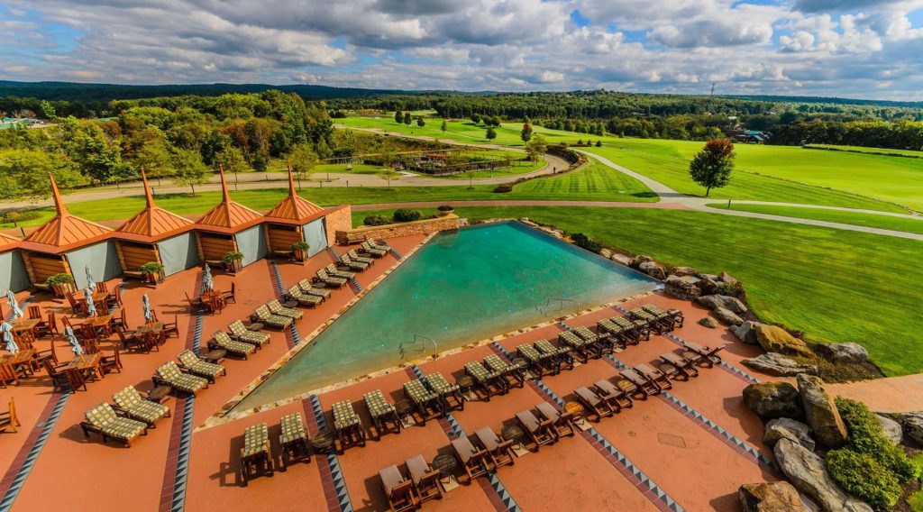Aerial view of Falling Rock infinity pool surrounded by lounge chairs and cabanas at Nemacolin