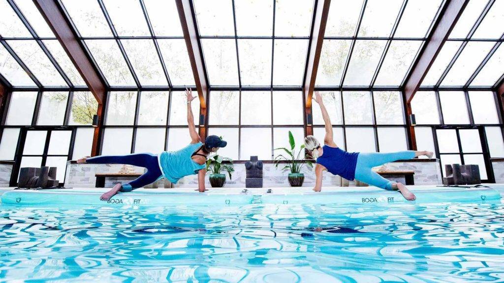Femmes faisant du yoga au bord d'une piscine intérieure à Nemacolin