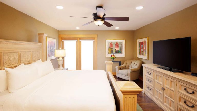 The Homes Deer Path Lodge - Rustic master bedroom with king bed, sitting area, and TV | Nemacolin