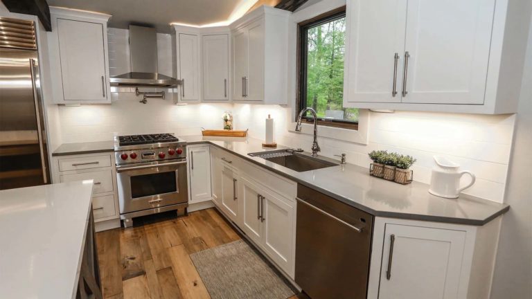 The Homes Greystone - Cuisine blanche à aire ouverte avec finitions modernes et électroménagers en acier inoxydable | Némacolin