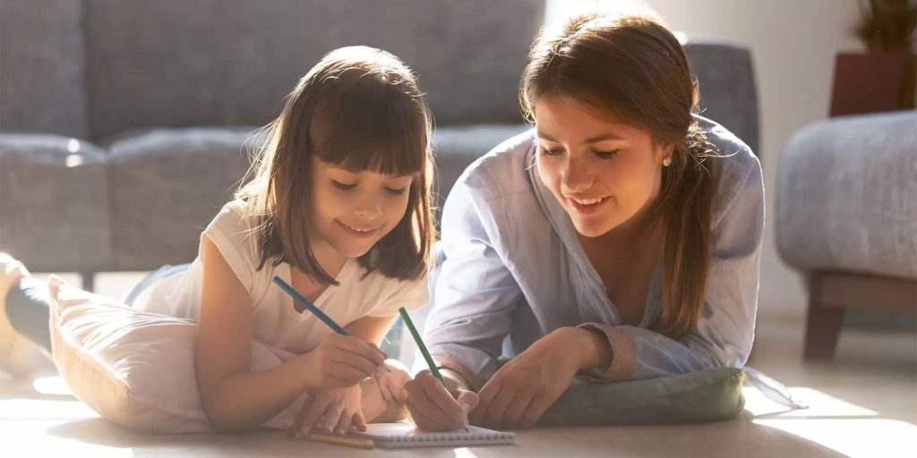 Baby-sitter et jeune fille travaillant sur un dessin au crayon de couleur chez Nemacolin