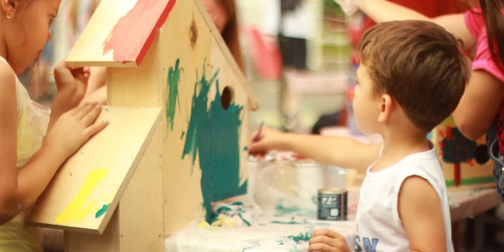 Group of children painting a birdhouse at the Kids Club | Nemacolin